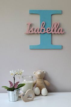 a teddy bear sitting next to a sign that says i and the letter j is made out of wood