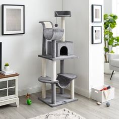 a cat is climbing on the top of a cat tree in a living room with white walls and hardwood floors