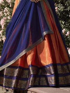 Embrace the vibrant elegance of our orange Kanchipuram silk lehenga, exquisitely paired with a blue Kanchipuram silk choli and a matching blue georgette dupatta. This ensemble showcases the rich heritage and craftsmanship of traditional Indian attire, featuring intricate zari weaving work that exudes luxury and sophistication. The orange lehenga, with its striking color and detailed design, is the perfect choice for making a bold statement at any grand event.
The lehenga offers a generous 3.70-m Orange Chanderi Lehenga With Cutdana, Semi-stitched Silk Orange Lehenga, Festive Orange Raw Silk Lehenga, Orange Silk Semi-stitched Lehenga, Orange Silk Lehenga For Festivals, Orange Chanderi Lehenga For Navratri, Orange Chanderi Lehenga With Dupatta, Anarkali Orange Raw Silk Lehenga, Orange Bollywood Chanderi Lehenga