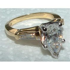 an engagement ring with a pear shaped diamond in the center and baguetts on each side