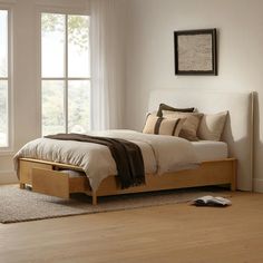 a bed sitting in a bedroom on top of a wooden floor next to a window