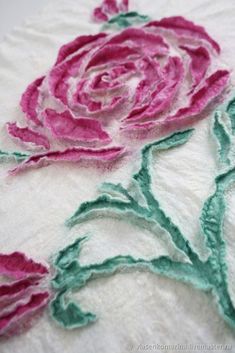 two pink roses on white fabric with green stems in the center and one red flower at the end