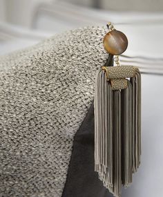 a pair of tasseled earrings hanging from the back of a gray and white chair