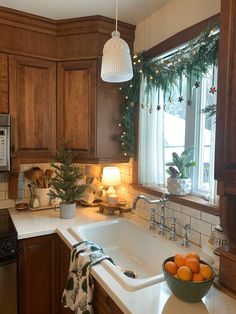 a bowl of oranges sitting on top of a kitchen counter next to a sink