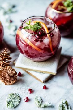 two glasses filled with fruit and garnish on top of napkins next to pine cones