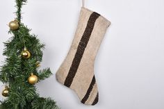 a christmas stocking hanging on a wall next to a small tree with gold ornaments