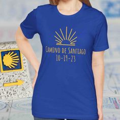 Cute Camino de Santiago keepsake souvenir tshirt gifts for completion of the Camino de Santiago de Compostela in Spain! The shirt is customized with the exact date the Camino was completed, making it a truly unique gift and personal memento.  A perfect t-shirt for a hike or a spiritual pilgrimage completed on the el Camino walk to Santiago de Compostela. This top is offered in six colors, including the color royal blue with yellow graphics--which are the symbolic colors of the Camino.  BTW - We have many Camino t-shirts, gifts & souvenirs: https://www.etsy.com/shop/GiftsByAuroraDesign?ref=seller-platform-mcnav&section_id=42884887 Thank you for choosing Gifts by Aurora Design. We have a passion for travel and fun adventures.  Check out our shop to see new items as they are introduced https: Blue Screen Print T-shirt As Gift, Blue Short Sleeve T-shirt For Gift, Blue T-shirt With Name Print For Gift, Blue T-shirt With Name Print As Gift, Summer T-shirt With Name Print For Gifts, Camino Walk, Souvenir Shirt, Aurora Design, Fun Adventures