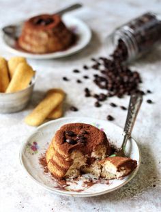 two plates with desserts on them and coffee beans scattered all over the table next to it