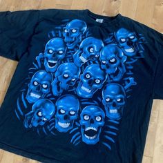 This piece is a vintage Liquid Blue skull pile t-shirt from the 1990s. This iconic tee from the brand has a design of blue skulls all over the front of the shirt. It is made from 100% cotton in a size 4XL and is in good vintage condition with regular wear and fading from age. There are no major stains, yellowing or flaws. Please also assess the photos and measurements carefully using your own personal judgement as we do not accept returns.Tag Size: 4XL *refer to measurements for true fit*Pit to Blue Grunge Tops For Streetwear, Blue Skull Print Crew Neck Top, Casual Blue T-shirt With Skull Print, Blue Short Sleeve Tops With Skull Print, Casual Blue Tops With Skull Print, Blue Band Merch Top For Streetwear, Blue Grunge T-shirt With Graphic Print, Blue Grunge Graphic Print T-shirt, 90s Blue Streetwear Tops