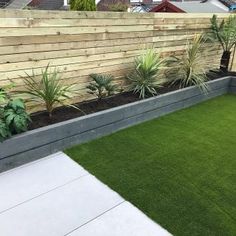 a garden with grass and plants in the middle, next to a fenced area