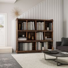 a living room filled with furniture and a book shelf next to a stair case full of books