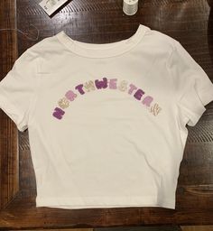 a white t - shirt with the word mother written in pink and purple on it