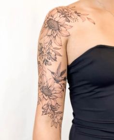 a woman wearing a black dress with sunflowers on her arm and shoulder tattoo