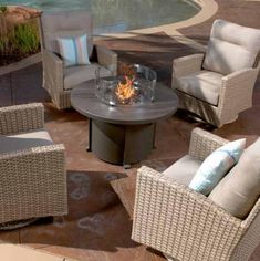 an outdoor fire pit surrounded by wicker furniture