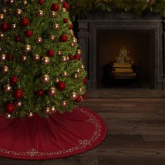 a christmas tree with red and gold ornaments in front of a fire place on the floor