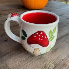 there is a cup with red liquid in it on the table next to a pumpkin