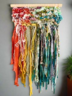 a multicolored scarf hanging on a wall next to a potted green plant