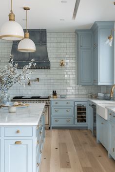 a large kitchen with blue cabinets and white counter tops, gold pulls on the handles