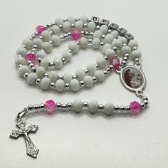 This beautiful and delicate personalized First Communion rosary for a girl or boy is a beautiful and meaningful gift for that special day of First Communion. This handmade religious jewelry is made with a beautiful Italian medal and the name of the boy or girl who will receive it and will be a permanent memory of that special day. It is a lasting reminder of God's love and blessing, as well as a special gift from godmother, aunt or grandmother to celebrate this important milestone and a reminder of faith that can be used daily. The perfect gift to express your love and faith! PRODUCT DETAILS: The Delicate Rosary is made with white glass, and with details in blue or pink depending on the case and silver details, as well as the name of the boy or girl who will receive it, made entirely by ha Adjustable Miraculous Medal For Gift, White Spiritual Necklace For Mother's Day, Spiritual White Necklace For Mother's Day, Mother's Day Gift Rosary With 8mm Beads, White Necklace For First Communion And Mother's Day, White Cross Jewelry For Personalized Gift, White Cross-shaped Jewelry For Personalized Gift, White Miraculous Medal Spiritual Jewelry, White Spiritual Cross Jewelry And Charms