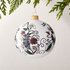 an ornament hanging from a christmas tree with leaves and flowers painted on it