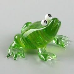 a green glass frog figurine with eyes on it's back