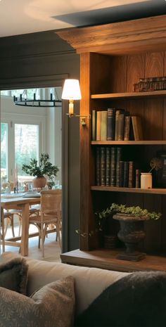 a living room filled with furniture and a book shelf next to a dining room table