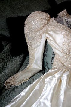 an old wedding dress is laying on the bed with its back turned to the camera