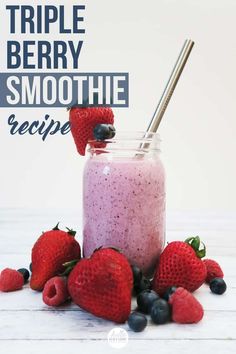 a smoothie in a glass with strawberries and blueberries on the side next to it