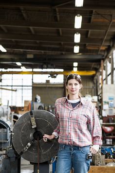 a woman standing in front of a large piece of machinery with one hand on her hip