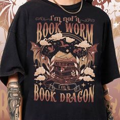 Fourth Wing Dragon Shirt, Book Lover T-shirt, Book Dragon Sweatshirt, Book Lovers Gift, I'm Not A Bookworm I'm A Book Dragon Shirt, Bookish 💖 WELCOME TO MY STORE 💖 THE STORE WILL REPLY TO MESSAGES IN 24 HOURS I. ABOUT PRODUCT - There are many ways to express your personality and wearing our products with eye-catching patterns and meaningful words is one of the ways. Comfortable, casual, and loose-fitting, our products will surely become one of your favorites. Made of 100% cotton, safe and comf Bookish T-shirt With Funny Print, Black Literary Top With Graphic Print, Literary Black Cotton T-shirt, Black Literary Crew Neck T-shirt, Black Literary T-shirt With Letter Print, Book Dragon Shirt, Dragon Sweatshirt, Dragon Shirt, Fourth Wing