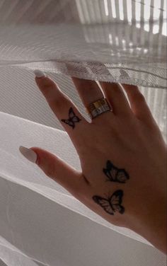 a woman's hand with butterfly tattoos on her left index finger and ring tattoo