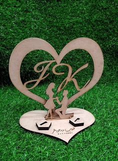 a metal heart with two people holding hands on top of it, in the grass