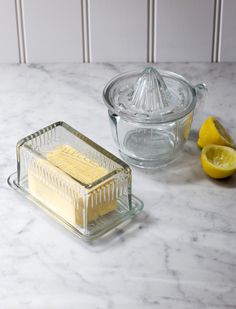 two lemons and a glass container on a marble counter