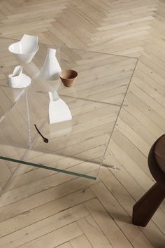 a glass table that has some bowls on it and a wooden chair in the background