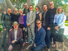 a group of people with clown noses posing for a photo in front of a tree