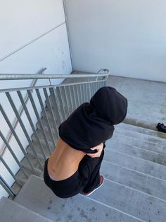 a person wearing a black hoodie climbing up some stairs with their hands on their hips