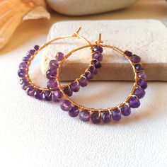 These hoop earrings are handcrafted in Italy with 14k gold plated wire and amethyst stones. They are elegant and versatile earrings, perfect for any occasion. Amethyst is a stone that symbolizes serenity and spirituality, and is an ideal gift for a special person. Earrings Features: Diameter: 3.3cm Stones: amethyst approximately 4 mm Structure: resistant but not rigid Closure: hook The photos are taken up close to illustrate details and give the impression of being larger. Please check the actua 14k Gold Filled Gemstone Hoop Earrings, Handmade Purple Jewelry In 14k Gold Filled, Elegant Gold Amethyst Hoop Earrings, Handmade Gold-plated Hoop Earrings, Purple Dangle Hoop Earrings As Gift, Handmade Gold-plated Round Hoop Earrings, Gold Small Hoop Earrings With Gemstones, Wire Wrapped Amethyst Round Earrings, Purple Amethyst Hoop Earrings For Gift