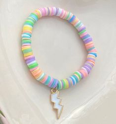 a colorful bracelet with a gold charm and a lightning bolt on the end is sitting on top of a white plate