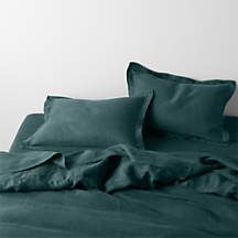 an unmade bed with green sheets and pillows