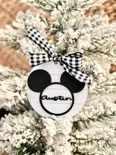 a mickey mouse ornament hanging from a christmas tree with the name disney on it