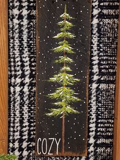 a painting of a pine tree on a black and white checkered background with the word cozy written below it