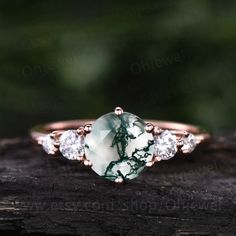 a green and white ring sitting on top of a piece of wood with diamonds around it