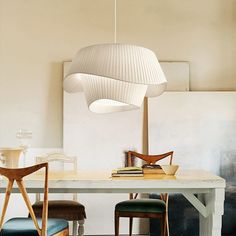 a table with two chairs and a lamp hanging over it in the middle of a room