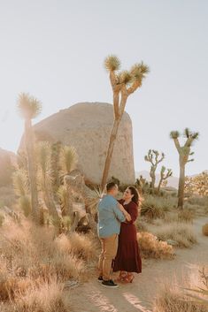 an engaged couple standing in front of a joshua tree