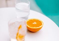 an orange sitting on top of a white table next to a glass filled with water