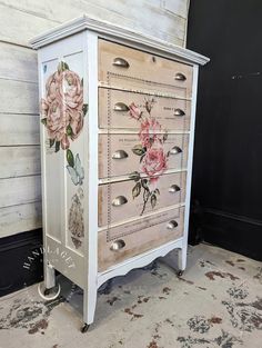 an old dresser with flowers painted on the front and drawers is sitting against a wall