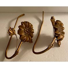 three brass flower hooks on a white wall