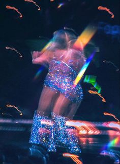 a woman is dancing in the dark with bright lights on her body and boots,