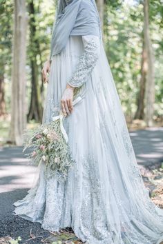 a woman in a wedding dress holding a bouquet and wearing a shawl over her head