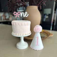 a pink cake sitting on top of a table next to a vase